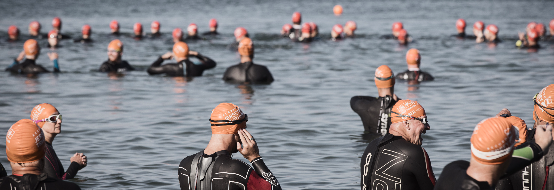Group of people in wetsuits getting into the ocean